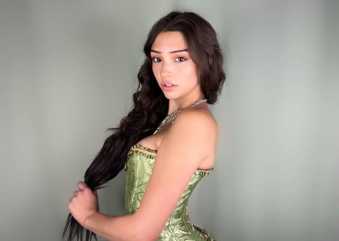 A young model with a relaxed, confident pose in soft natural light, wearing a stylish outfit that matches a clean, minimal aesthetic.