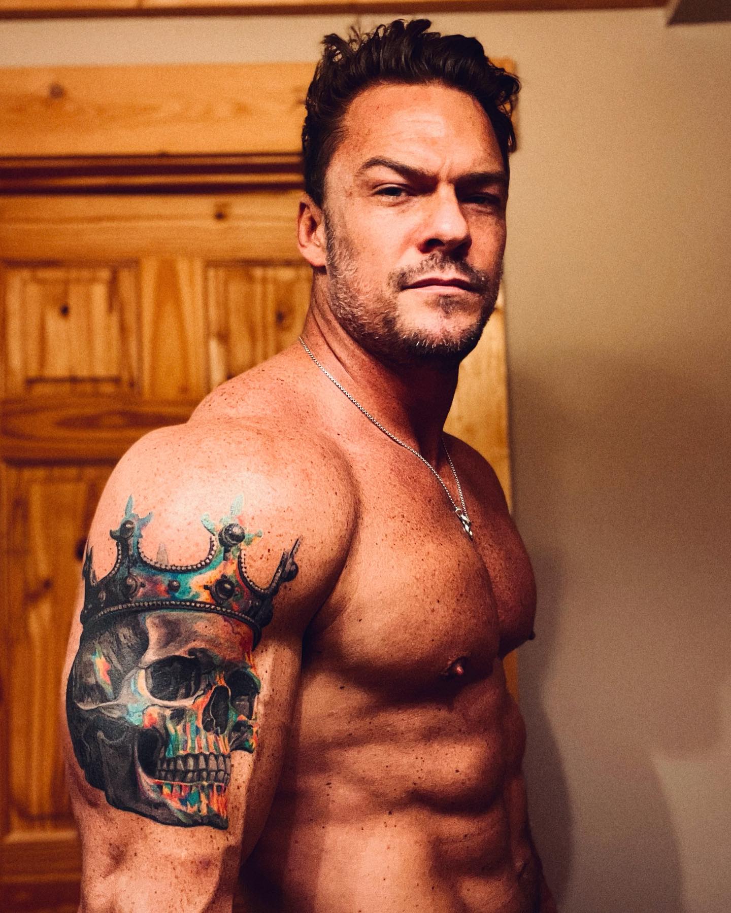 Alan Ritchson standing in a doorway, broad-shouldered and towering, conveying the imposing presence of Jack Reacher