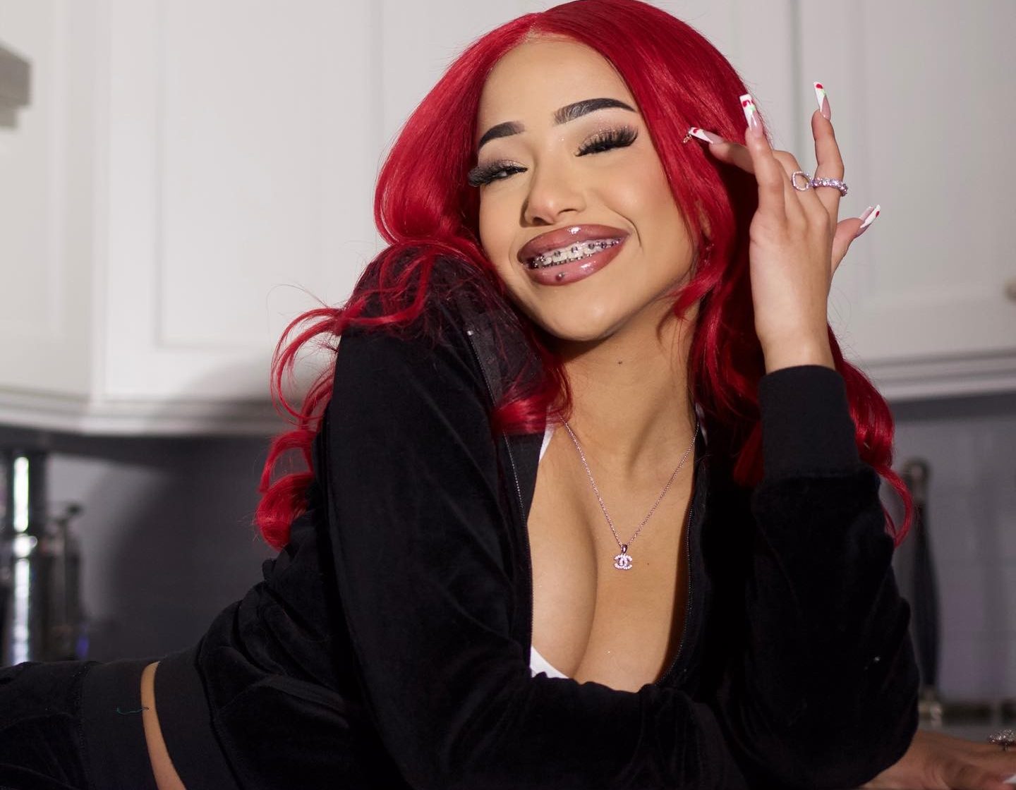 Aya Tanjali smiling and performing a short dance move in a casual home setting, emphasizing her expressive style and playful personality