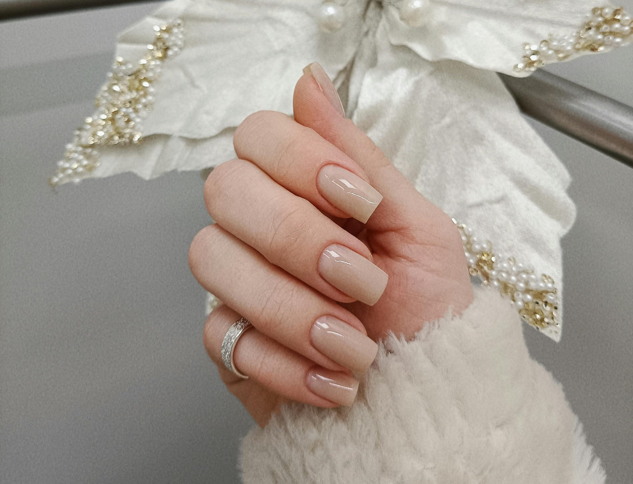 Close up of winter white nails with a glossy finish against a soft knit sweater