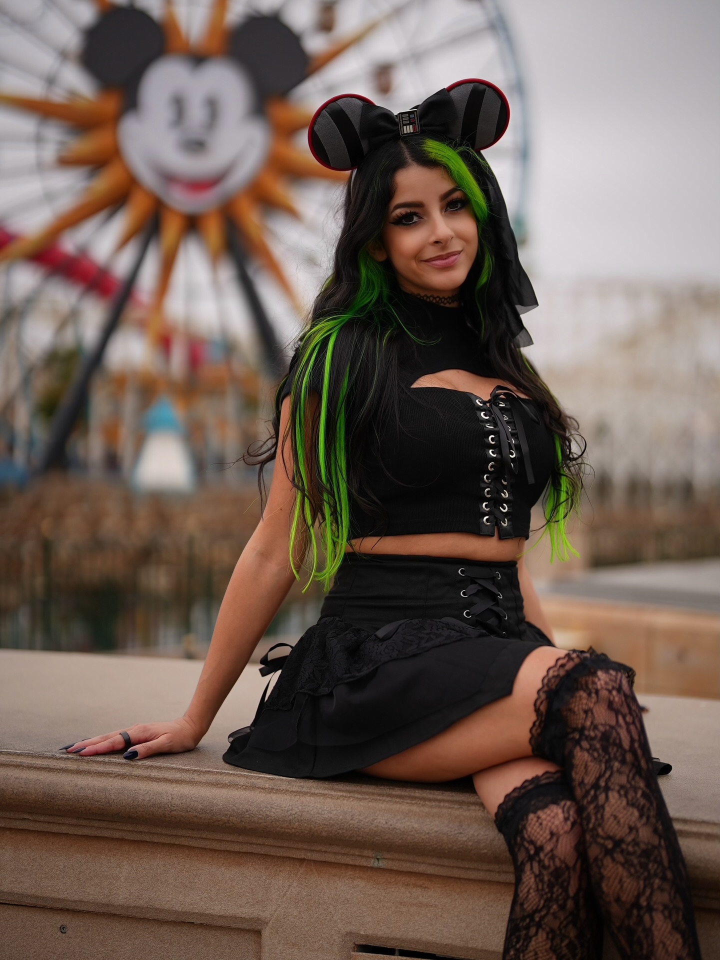 Cosplay creator in a glossy, colorful outfit striking a playful pose under studio lighting