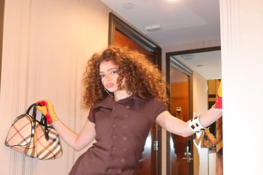 Demitra Kalogeras posing in a fashion forward outfit while mid movement as if dancing, confident expression and bright lighting