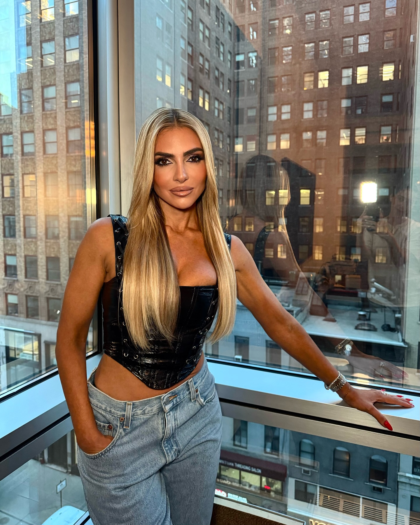 Eleonora Srugo speaking with clients in a modern Manhattan apartment, reflecting her real estate expertise and polished public presence