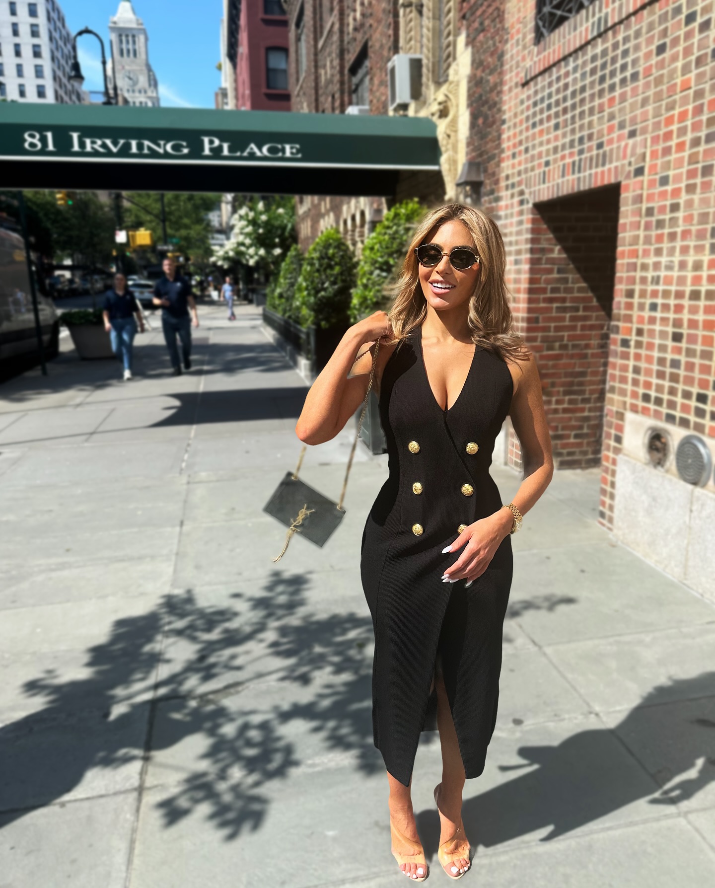 Eleonora Srugo speaking with clients in a modern Manhattan apartment, reflecting her real estate expertise and polished public presence