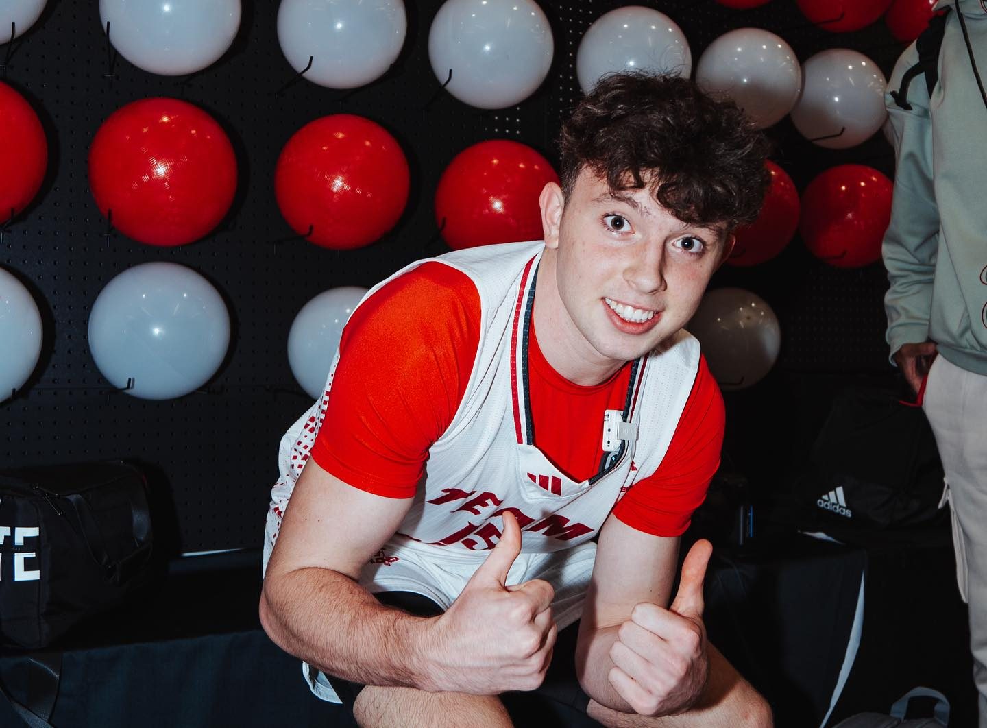 Eli Ellis dribbling a basketball on an indoor court, focused and in motion with teammates in the background
