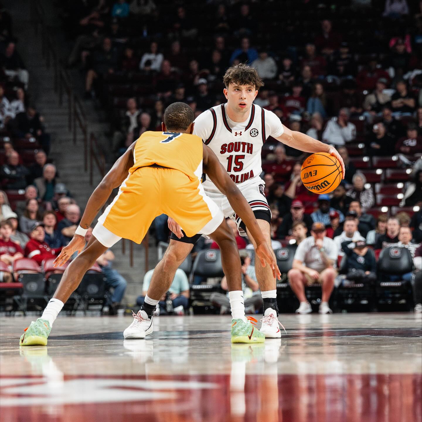 Eli Ellis dribbling a basketball on an indoor court, focused and in motion with teammates in the background