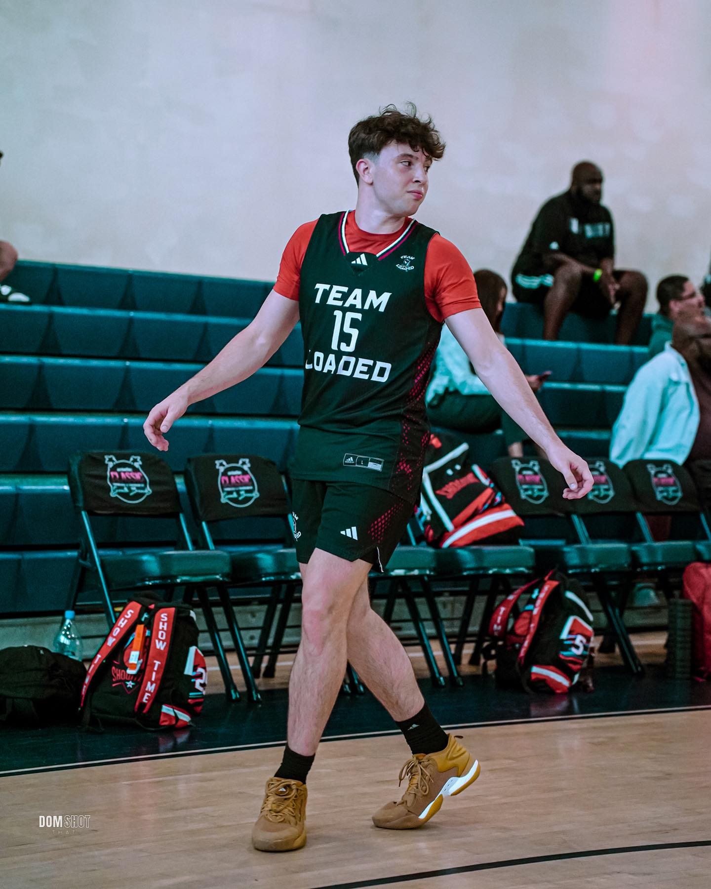 Eli Ellis dribbling a basketball on an indoor court, focused and in motion with teammates in the background