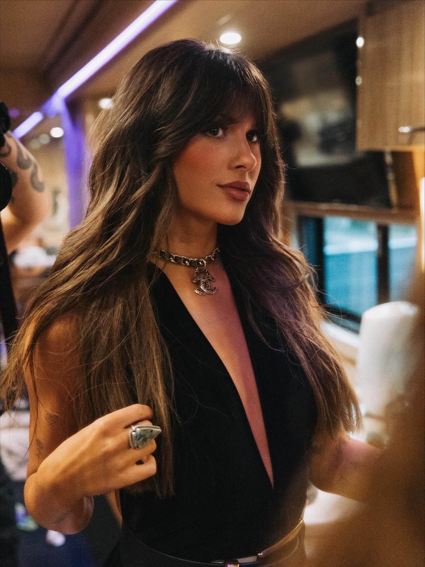 Ella Langley performing on stage with a guitar, spotlighted against a dark backdrop, conveying the emotional intensity of her country songs