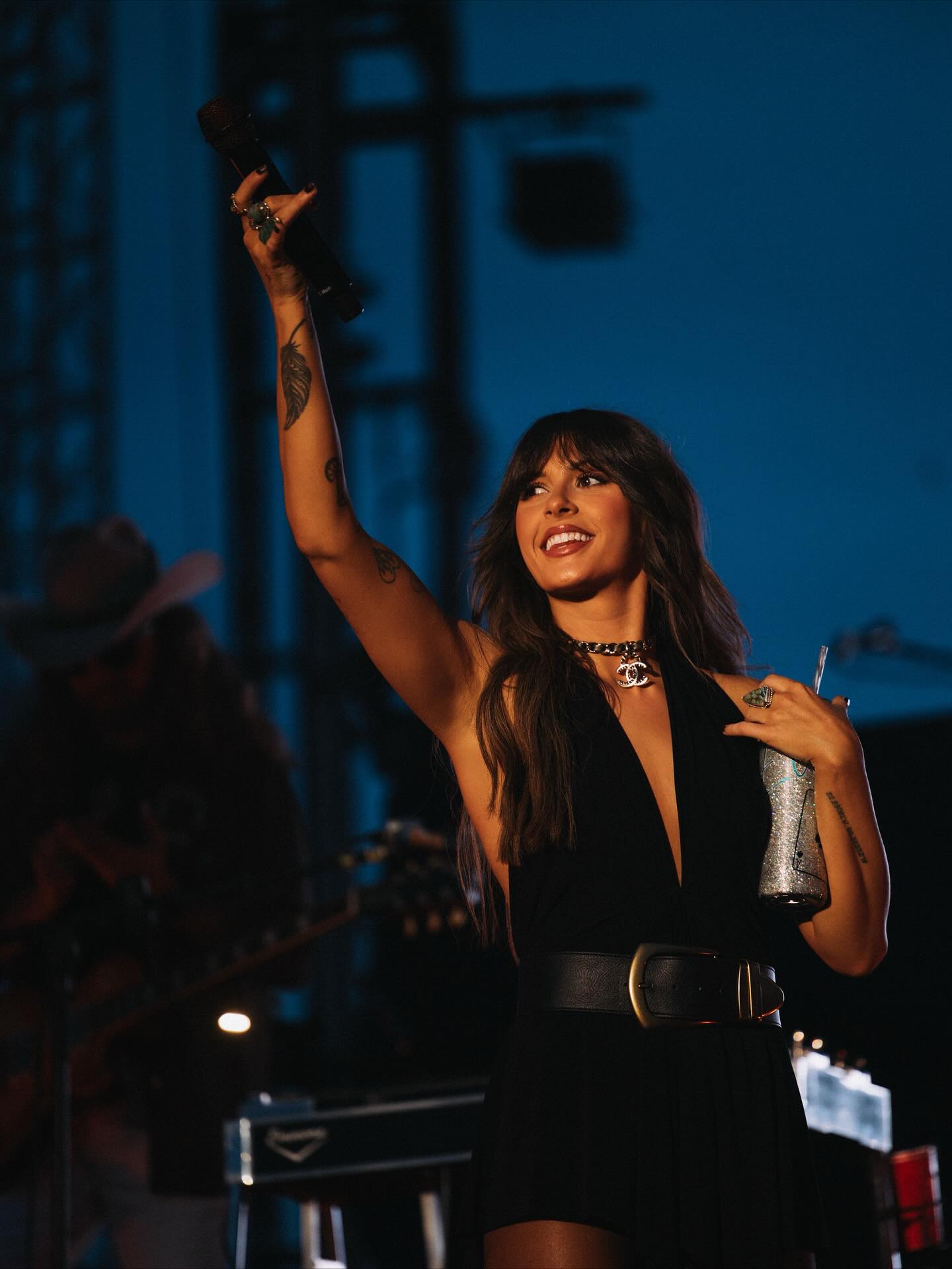 Ella Langley performing on stage with a guitar, spotlighted against a dark backdrop, conveying the emotional intensity of her country songs