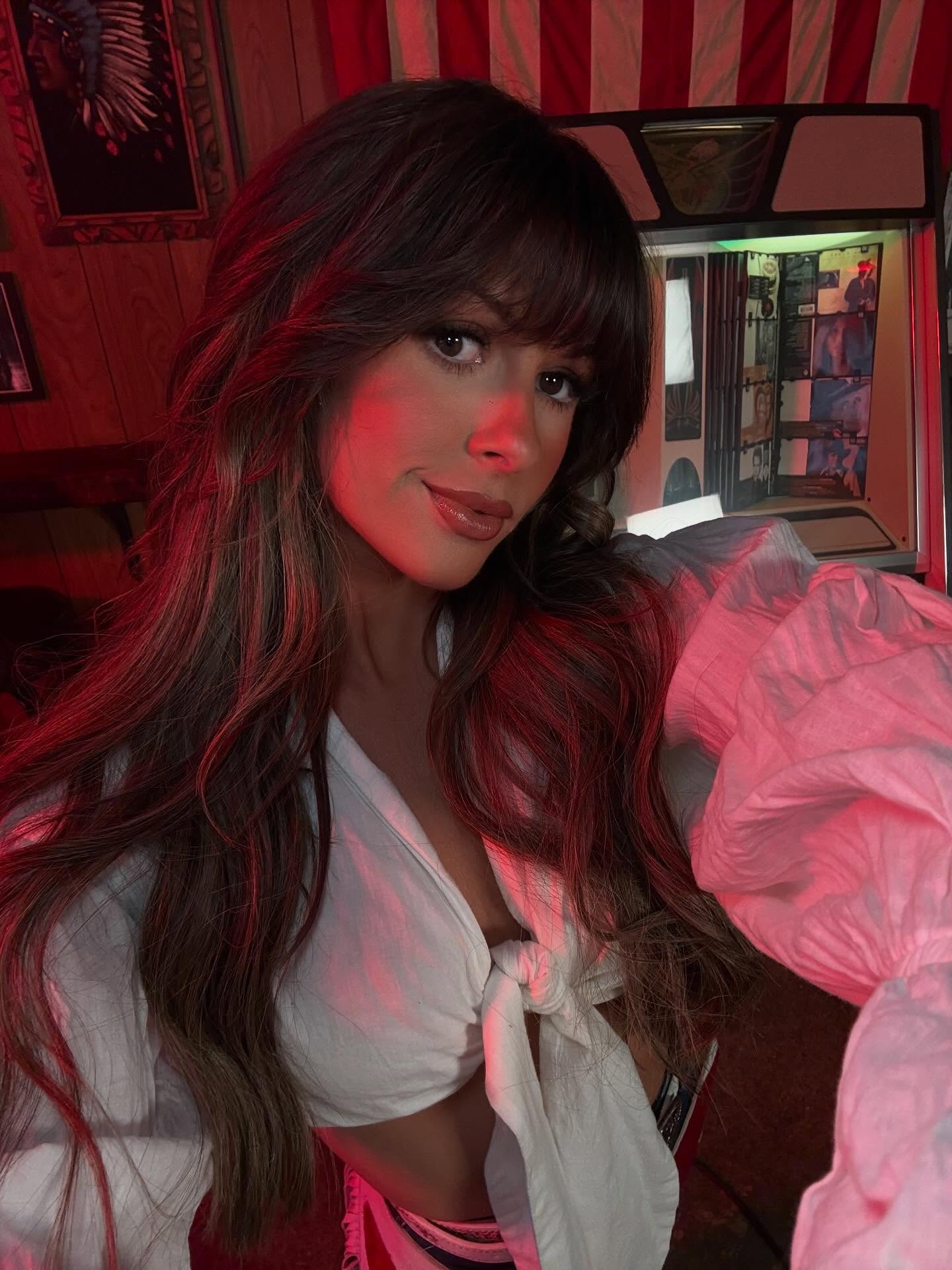 Ella Langley performing on stage with a guitar, spotlighted against a dark backdrop, conveying the emotional intensity of her country songs