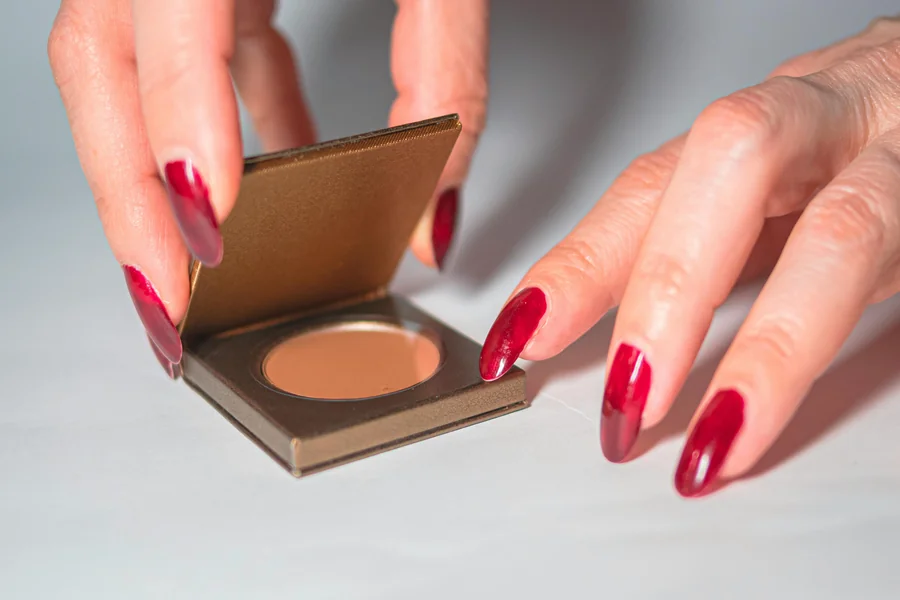 Close up of hands with modern French tip nails featuring a sheer base and slim, glossy white edges on oval shaped nails