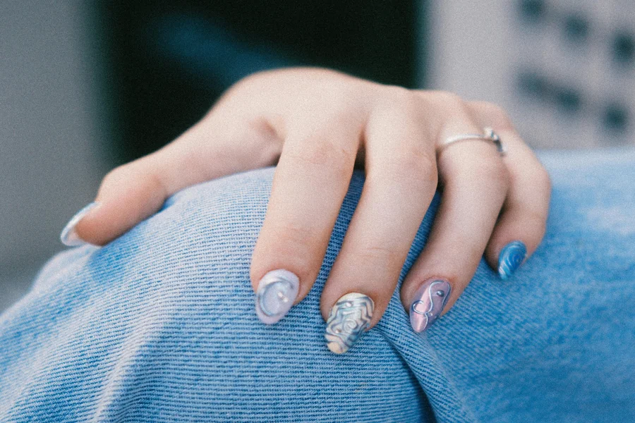 Hand in a knit sweater holding a warm beverage with glossy navy blue winter manicure