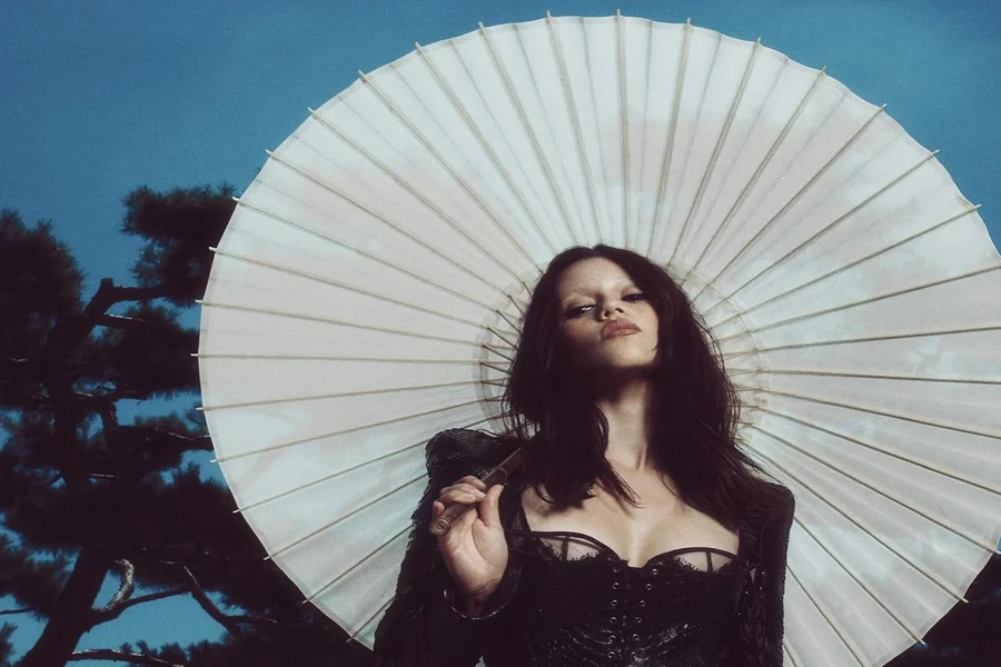 Jenna Ortega on a red carpet in a sleek monochrome look with platform heels, emphasizing her petite frame and confident presence.