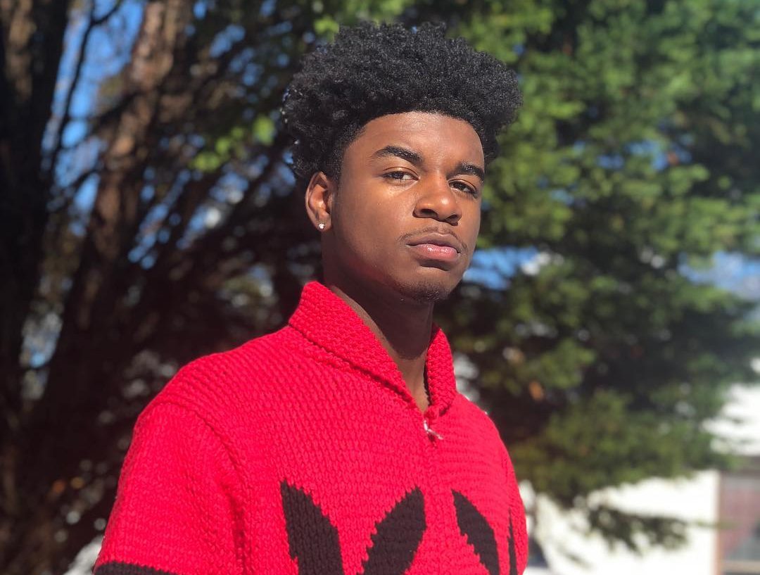 Ken Carson performing on stage under dark, futuristic lighting with an energized crowd.