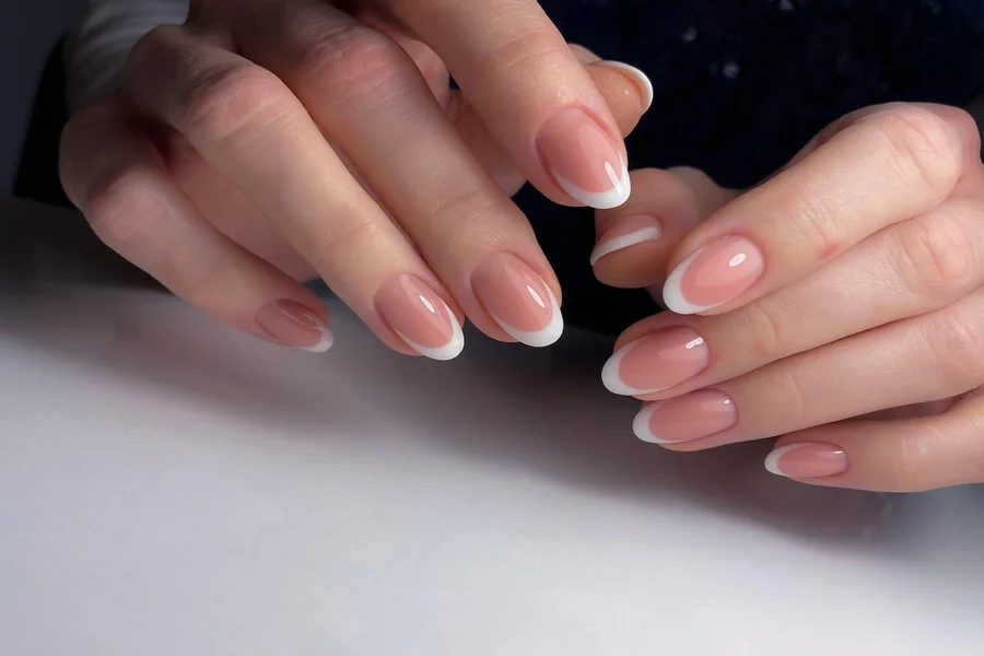 Close up of hands with modern French manicure featuring colored tips and clean neutral bases