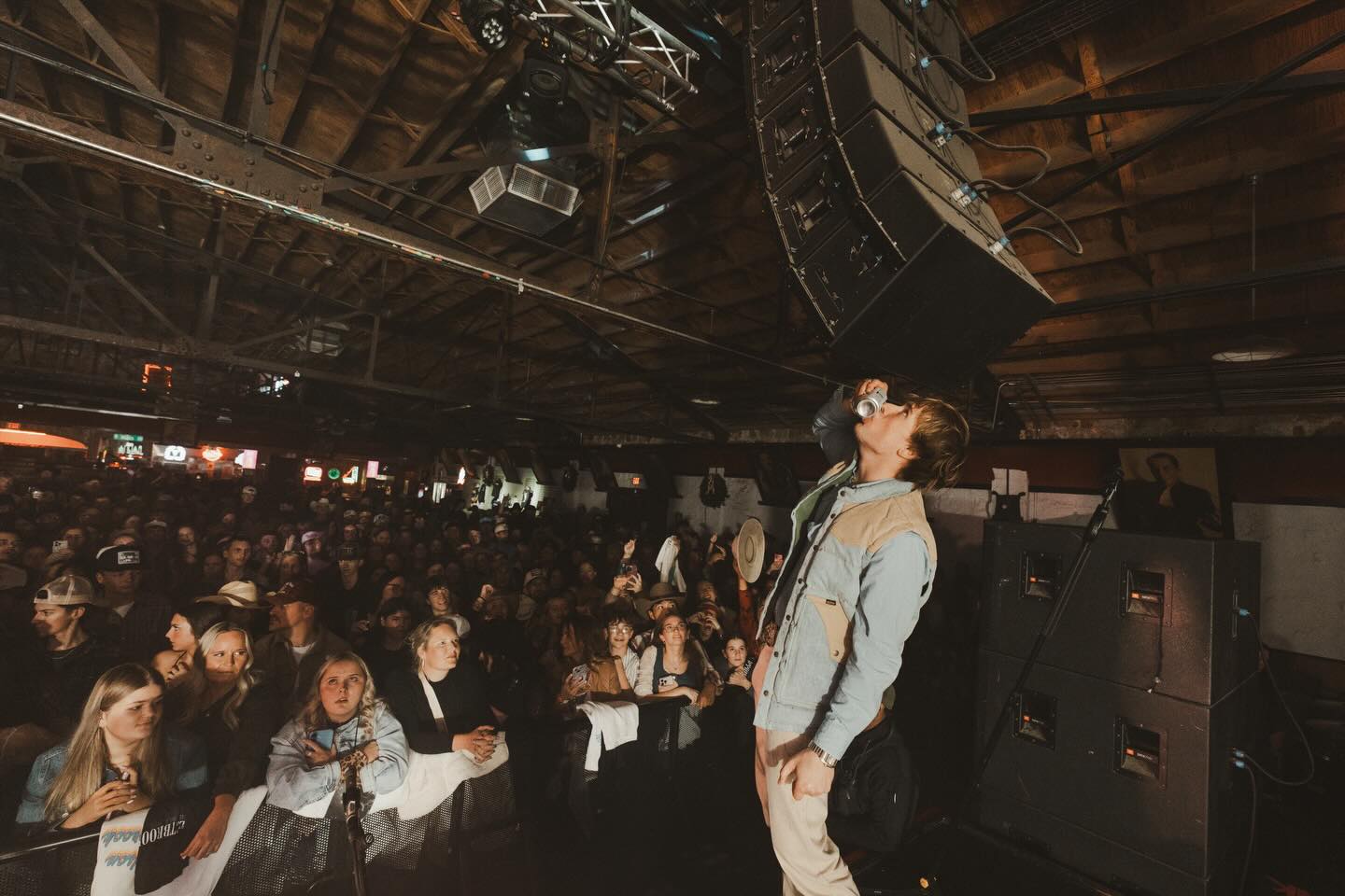 Hudson Westbrook performing on stage with a guitar under warm Texas lights, reflecting the storytelling heart of country music