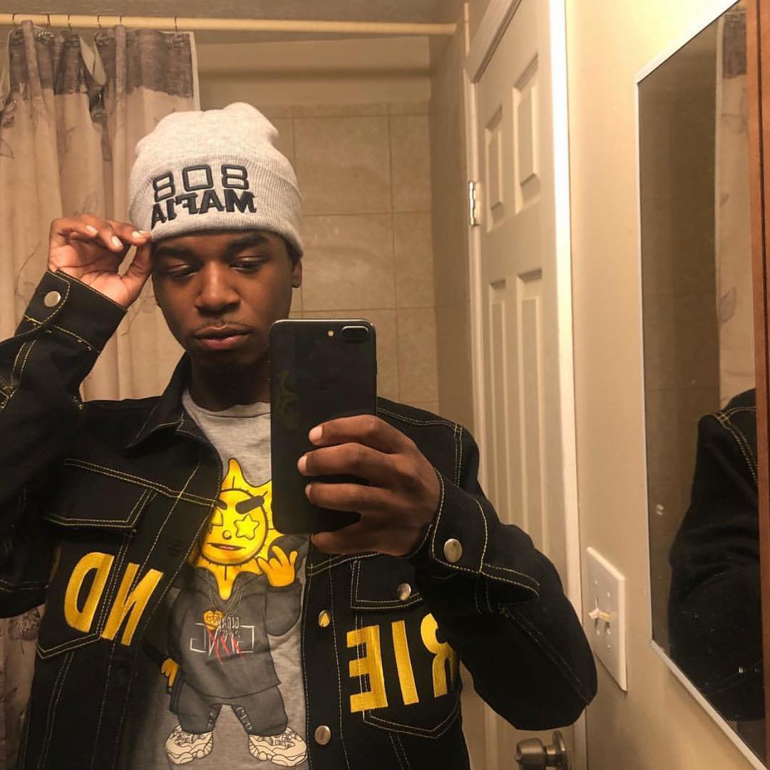 Ken Carson performing on stage under dark, futuristic lighting with an energized crowd.