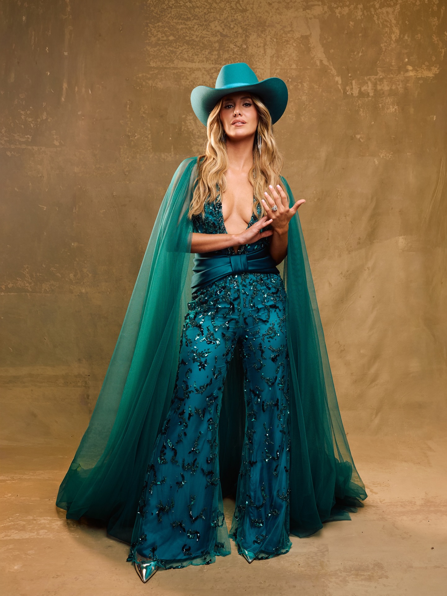 Lainey Wilson performing on stage in vintage-inspired attire with a microphone in hand and warm stage lighting