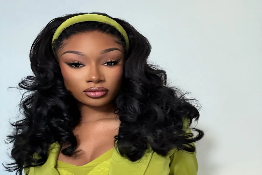 Megan Thee Stallion standing tall on stage in high heels, commanding the spotlight with confident posture.