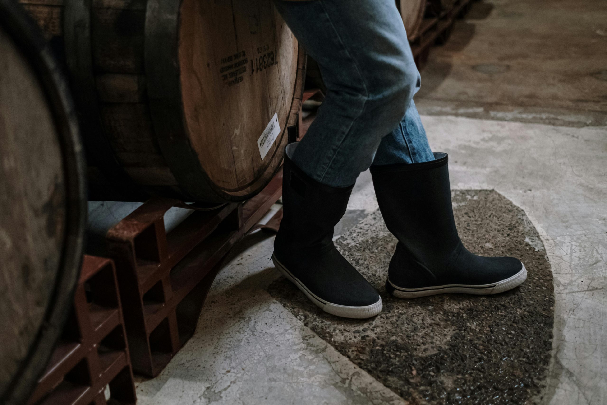 Person wearing barrel jeans with a curved leg and tapered ankle, styled with a fitted top and ankle boots.