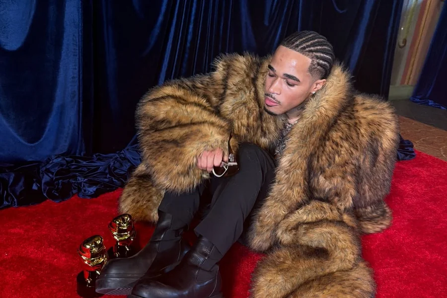 Plaqueboymax streaming at a desk with music production gear, microphone, and chat window visible on screen