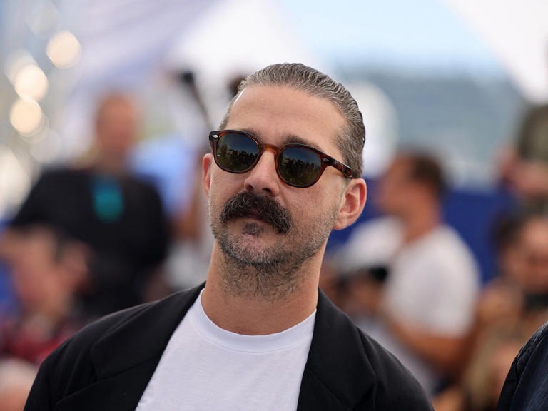 Portrait of Shia LaBeouf at a public event, wearing a tailored suit and looking slightly off camera